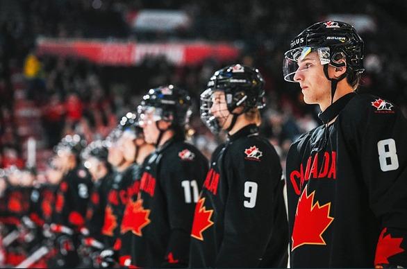 Hockey players from team Canada standing in line in a hockey arena full of fans