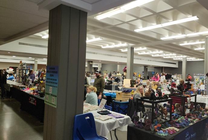 Craft fair buzzes with handmade goods—tables brim with art, people browse, lights glow above.