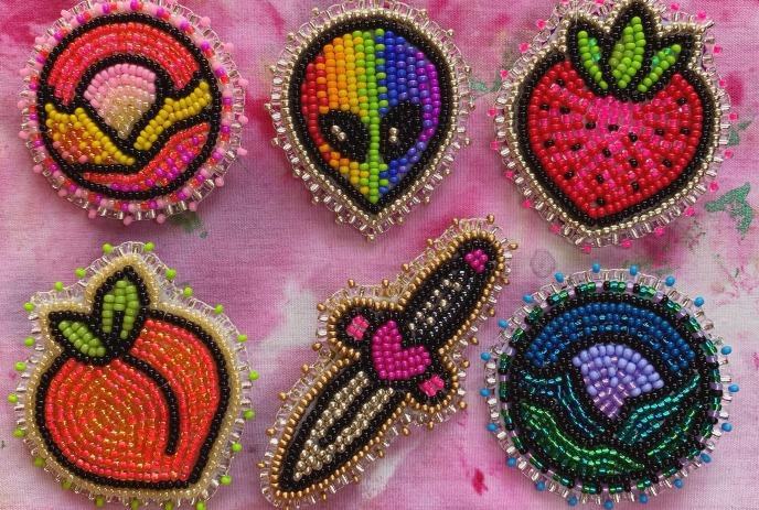 Six colorful handmade beaded patches feature fruits, an alien face, a dagger, and a rainbow motif.