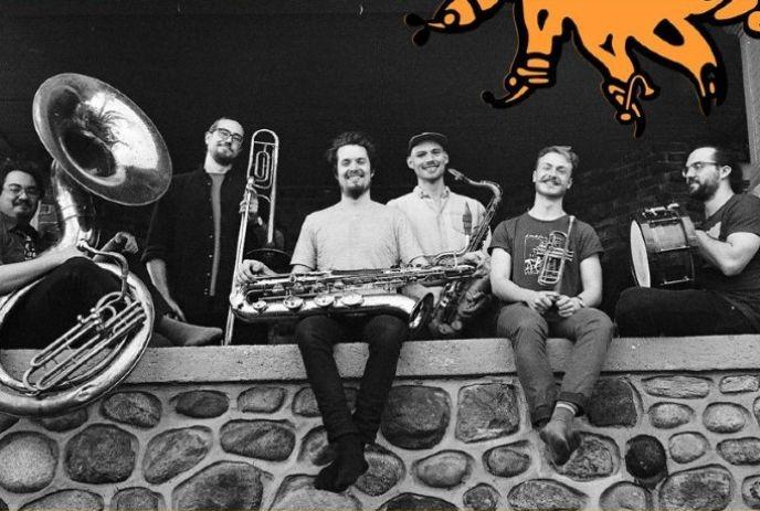 A band with their instruments, sitting on a stone wall posing for the camera.