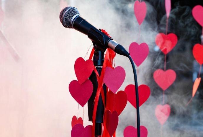 A microphone on a foggy stage decorated with red paper hearts.
