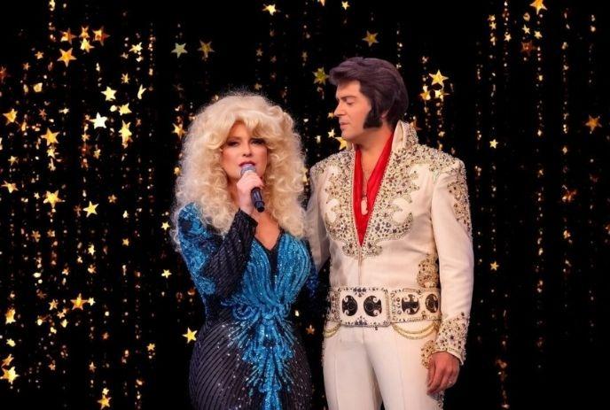 Dolly Parton & Elvis are dressed in 1970s glam outfits against a sparkling starry backdrop.