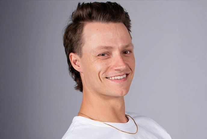 Smiling person in white shirt and necklace, with short hair, set against a dark backdrop with maple leaf symbols.