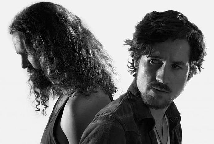 A black and white photo of the two band members of Black Pistol Fire, looking different directions, away from the camera.