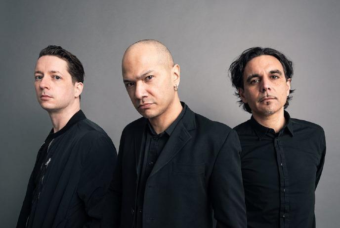 The band Danko Jones, three members in black attire staring intently against a gray backdrop.