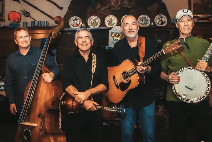 Four band members with their instruments, smiling for the camera.