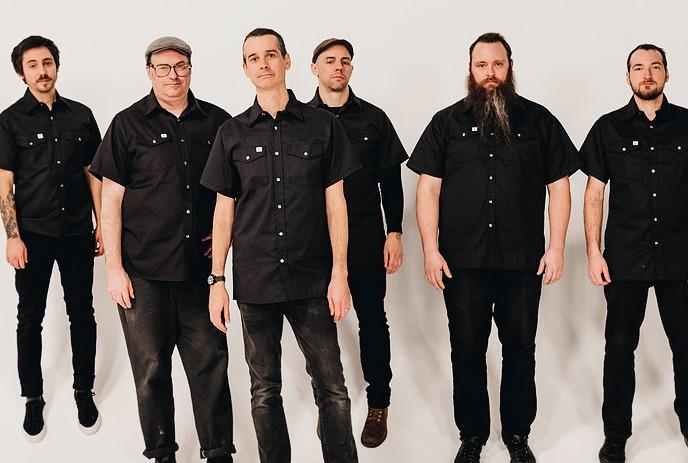 6 band members of The Planet Smashers all wearing black, posing for a photo against a white background.