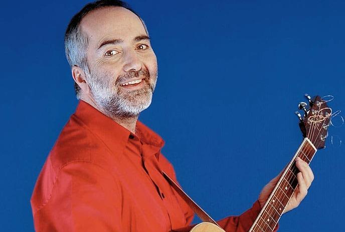 Musician Raffi holding an acoustic guitar