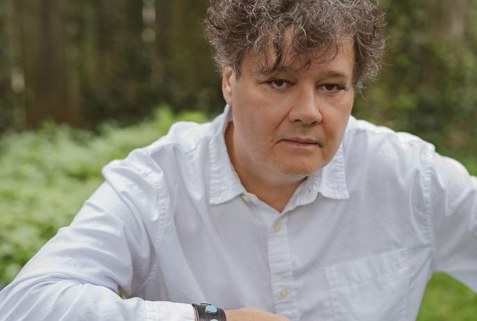 Ron Sexsmith posing in front of a brightly coloured shipment crate.