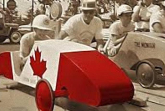 Red and white soapbox car with maple leaf, with people in sepia behind it.