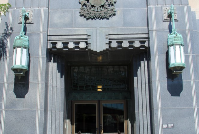Front door of the Dominion building with two lamp standards hanging outside.