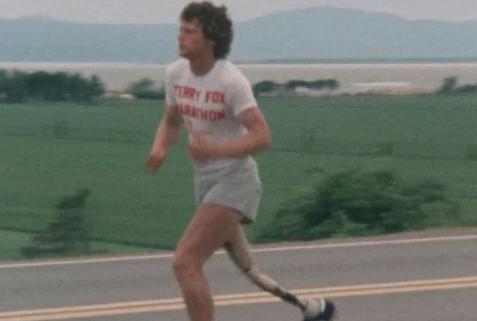 Terry Fox running on the highway with rolling hills in the distance.