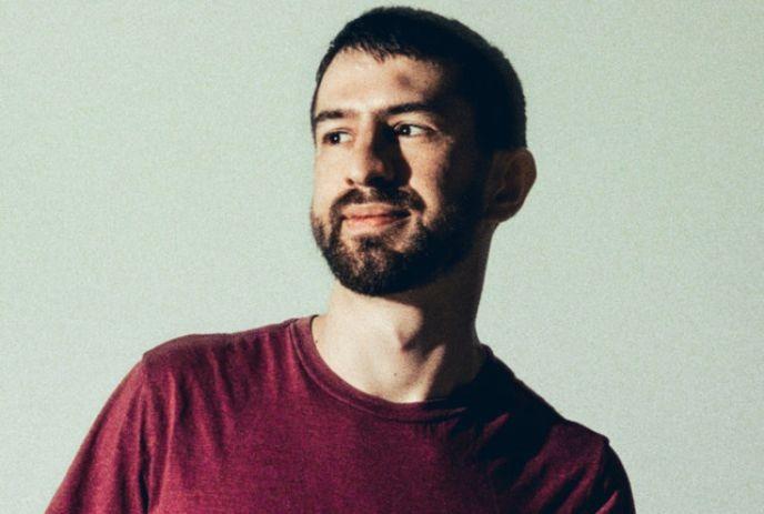 A headshot of Mat Zo, in front of a light green background.