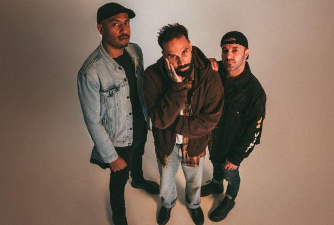 Letlive. band members stand together, viewed from above against a plain beige studio backdrop with calm, serious expressions.