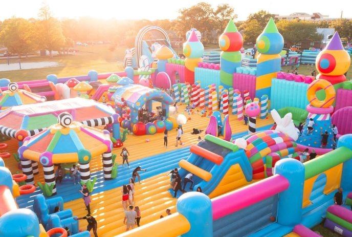 A colorful inflatable playground with multiple slides and climbing structures, with people actively enjoying the area.
