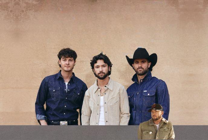 Four men are standing against a beige background, two wearing denim shirts and two in a light-colored jacket posing.