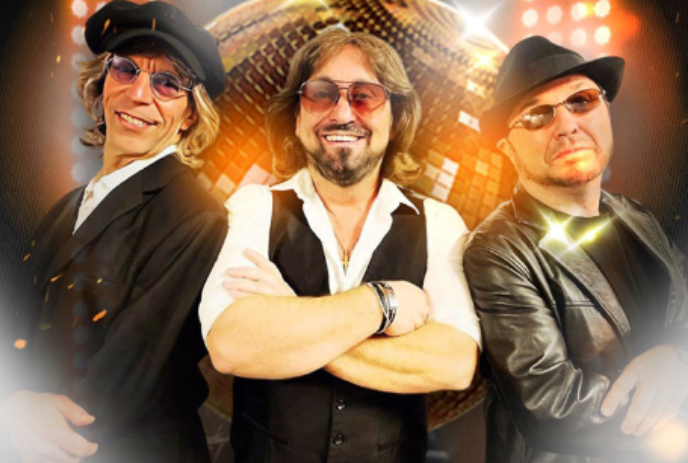 Three band members wearing sunglasses, posing in front of a disco ball.