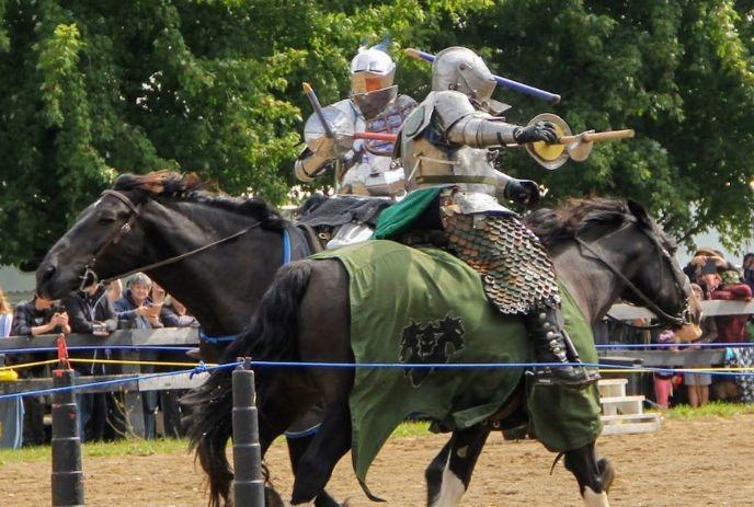 A dynamic scene at the Oxford Renaissance Festival featuring a knight in full armor riding a dark horse.