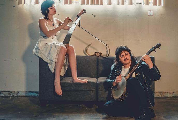 The two band members of Willow Switch, posing on a couch together.