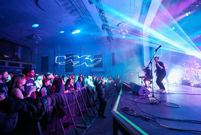 Concert scene of Wing Night band performing with colorful lights and a lively crowd.