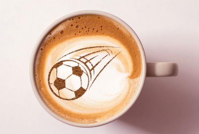 A cup of coffee with a soccer ball design in the foam.