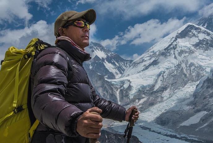 An explorer wearing winter gear on the top of a mountain.