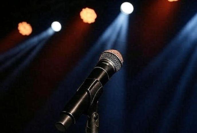 A microphone on stage with lights in the background.