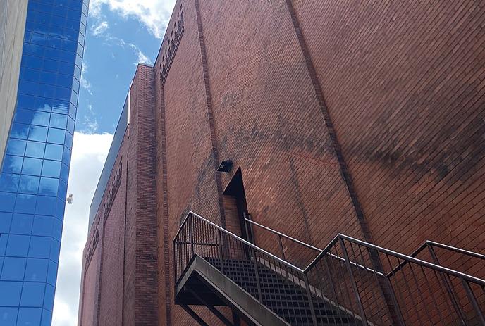 Looking up between the Grand Theatre and another building with windows all the way up.