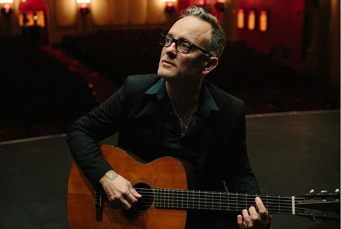 Dave Hause posing with his guitar, looking off into the distance.