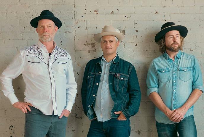 Members of Elliott Brood posing against a brick wall.