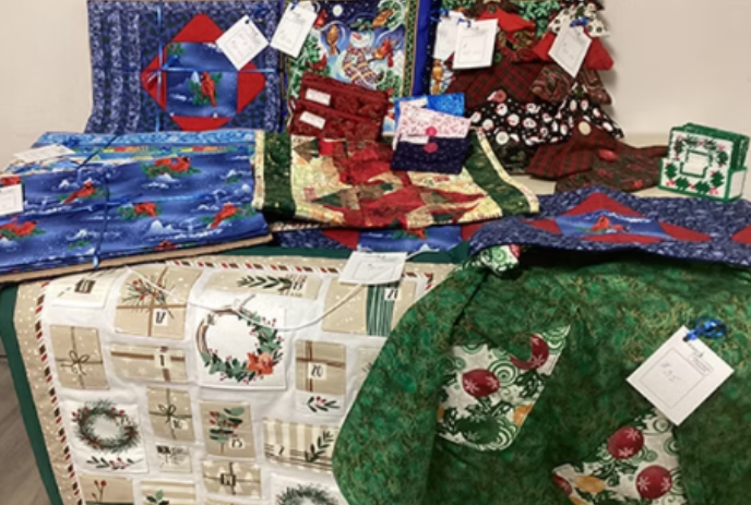 Numerous quilts displayed on a table.