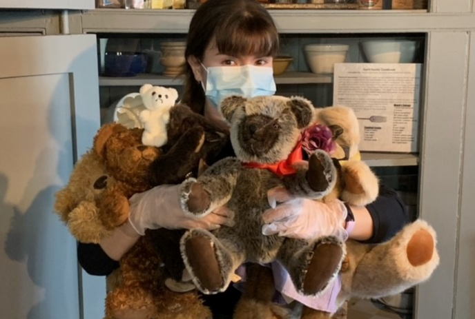 Young person with arms full of a bunch of teddy bears.