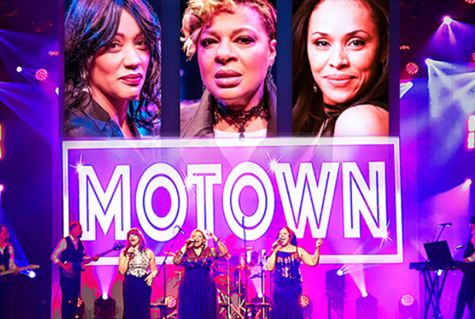Group on stage singing with photos above a Motown sign.