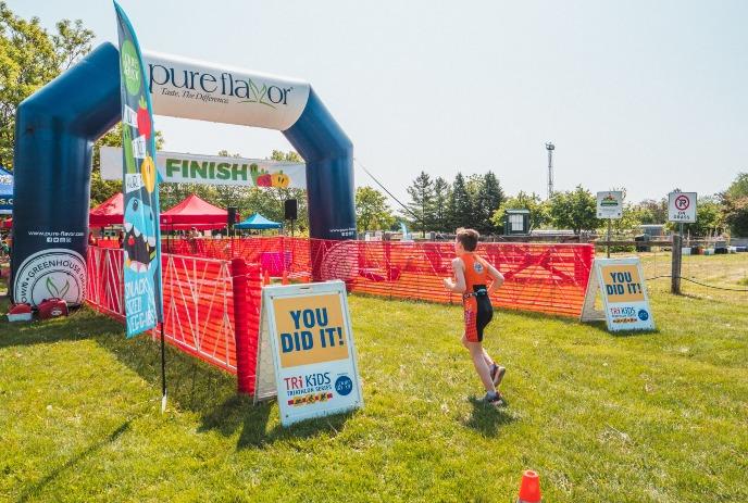 A kid participating in a running event outdoors in the sunshine.