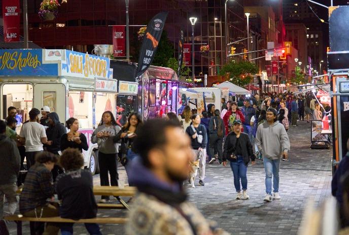 People walking on a downtown street with vendors lining the walkways.