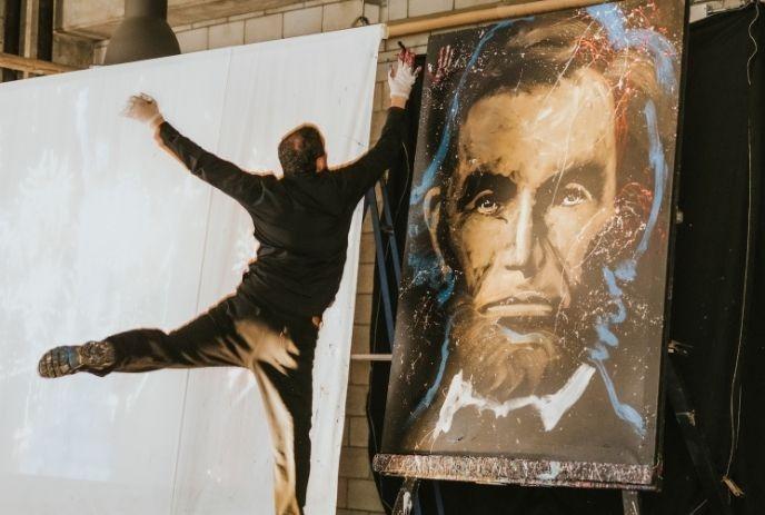 A person places their handprint on a painting of Abraham Lincoln.