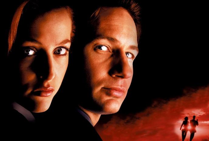 Two dramatic faces loom close in deep shadow, while two small figures run off toward a glowing, fiery red horizon.