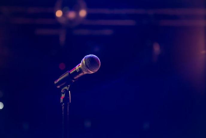 A microphone on stage bathed in purple light.
