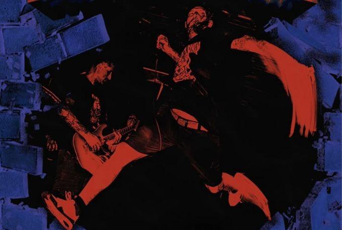 A red and blue graphic captures a guitarist playing alongside a singer jumping mid-air in front of a broken brick wall.