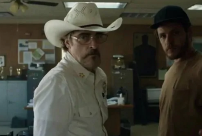 Person wearing a cowboy hat looks away from another person standing in front of them.