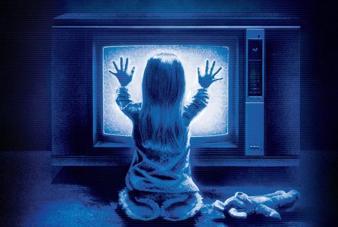 Child on the floor, hands pressed to glowing static TV screen, in blue light with toy nearby.