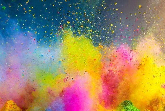 Vibrant clouds of pink, yellow, green, and blue powder burst together in the air.