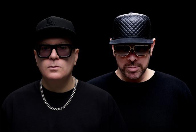 Headshots of Manzone & Strong, looking expressionless at the camera in front of a black background.