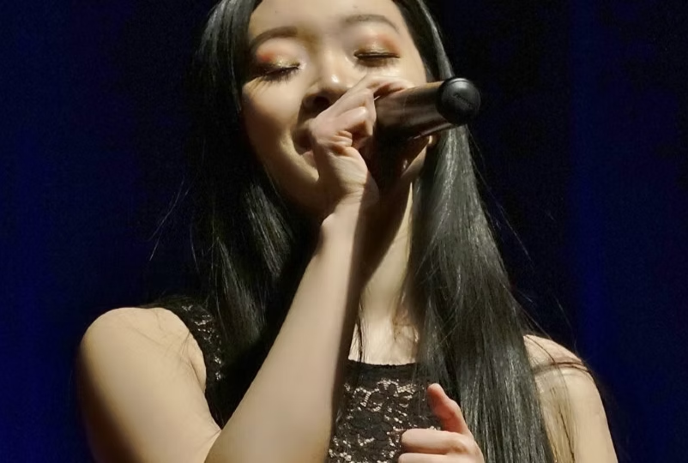 Nicole Tan singing on stage with a microphone.