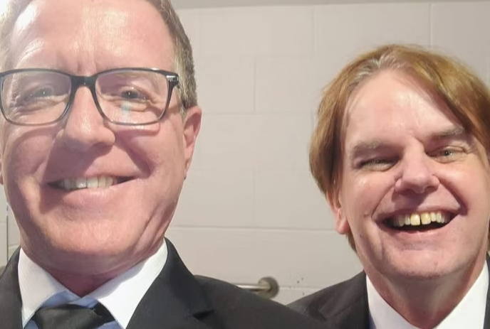 A picture of Ron Walker & Iain McNally smiling together, wearing suits.