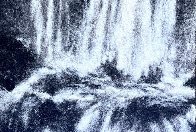Abstract textile with soft white fibers on dark fabric, creating a flowing pattern that resembles a cascading waterfall.