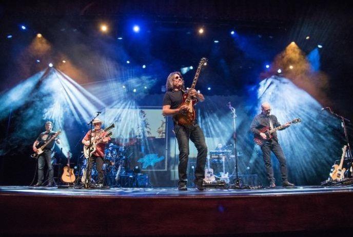 Band members on stage playing with blue lights in the background.