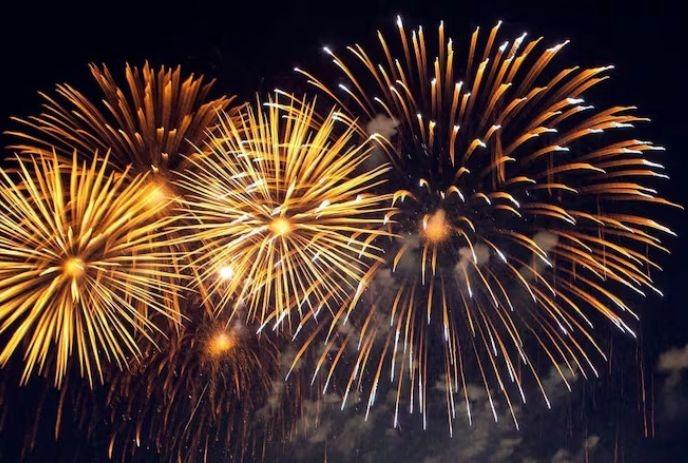 Multiple fireworks in yellow, orange and white colours under the black sky