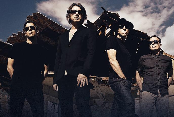 54-40 posing outside wearing dark clothes and sunglasses on a cloudy day.