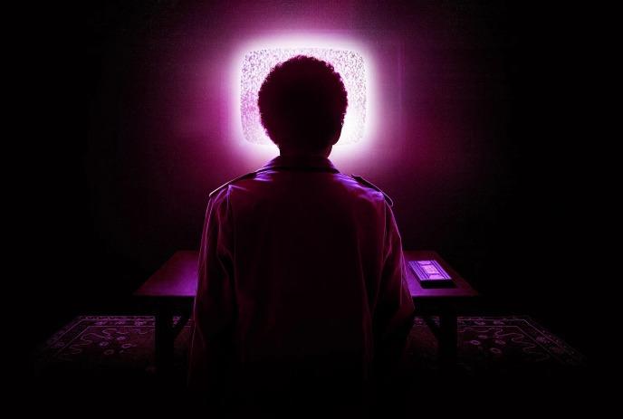 A person sits in pitch darkness, staring directly into the brilliant, neon pink glow of a static-filled television screen.